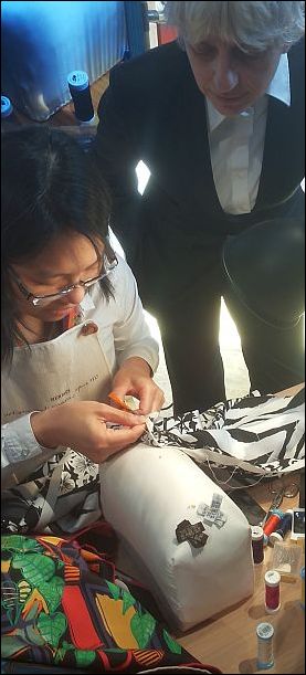 Het zomen van een zijden sjaal, met behulp van een steunkussen, met de hand.